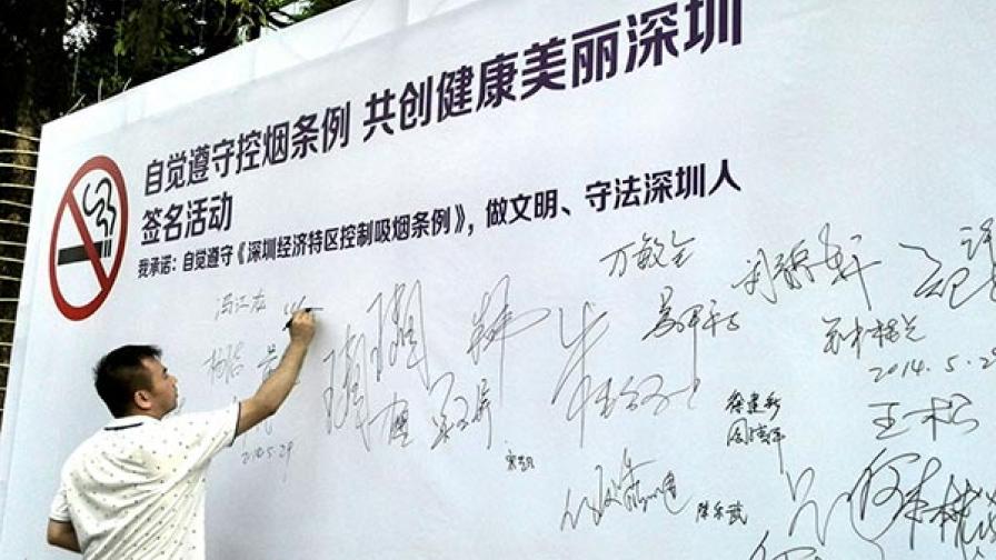 A resident of Shenzhen adds his signature to an anti-smoking wall on World No Tobacco Day.